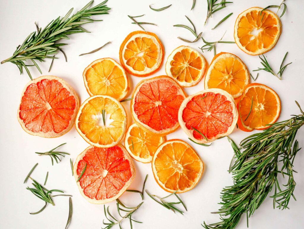 rodajas de naranjas y limones con romero sobre una superficie blanca