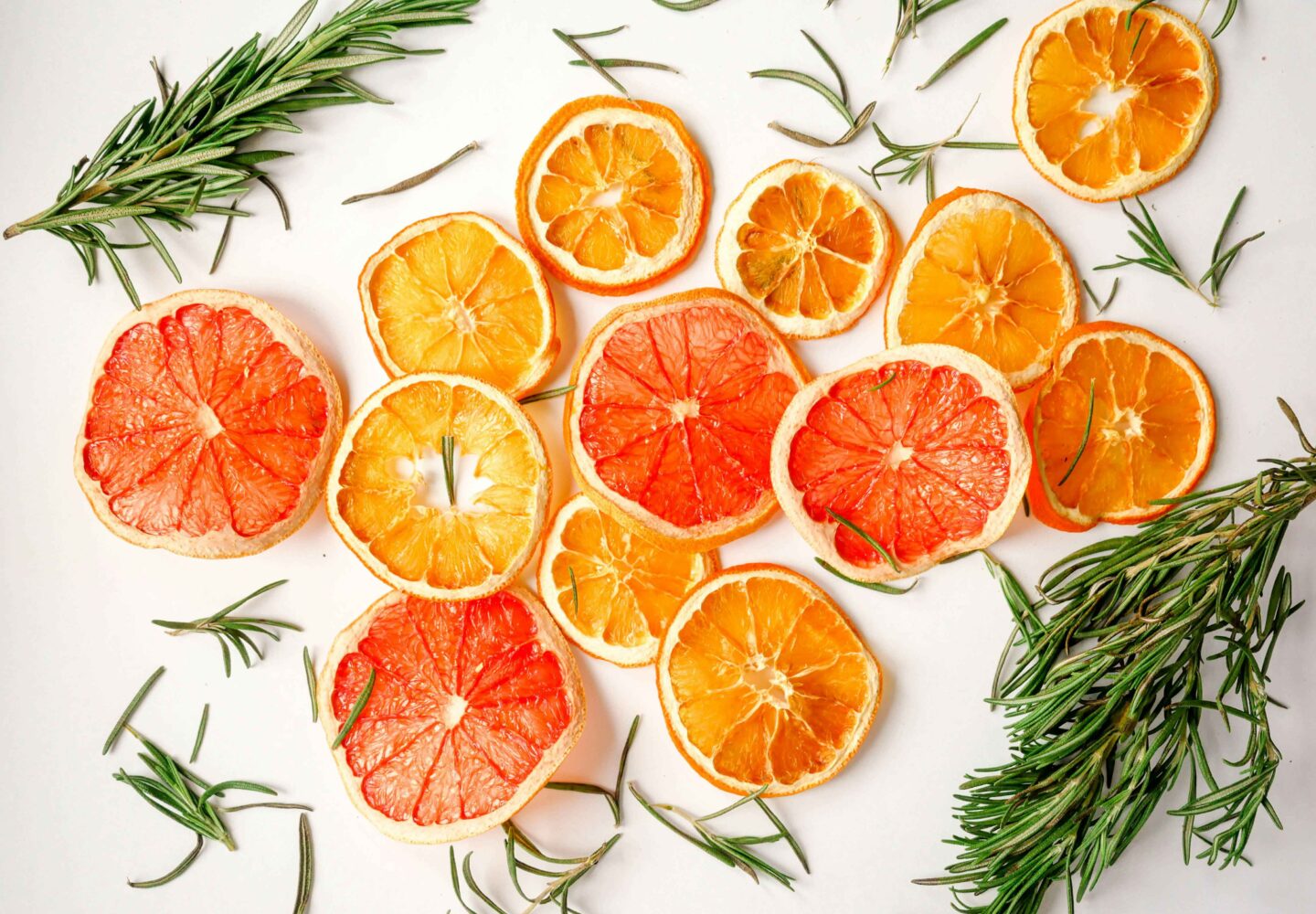 slices of oranges and lemons with rosemary on a white surface